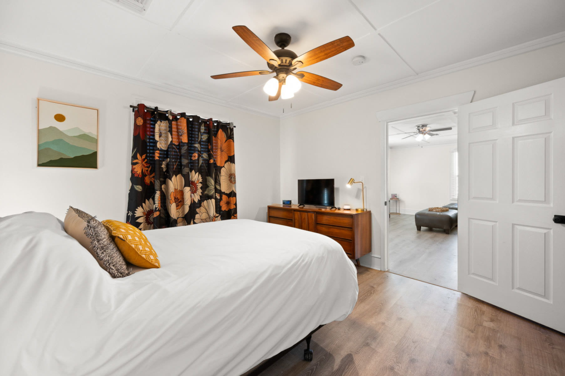 Bedroom with floral curtains and a view to the dining area